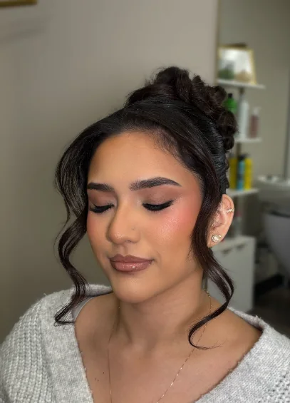 Client with soft glam makeup and a curled, face-framing updo