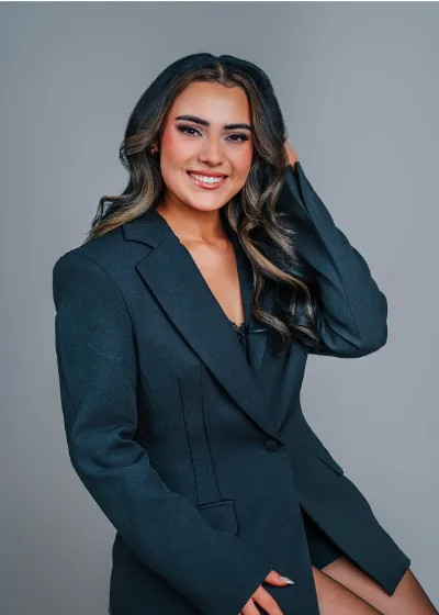 Nevaeh Perez smiling in a dark blazer, long wavy hair over one shoulder
