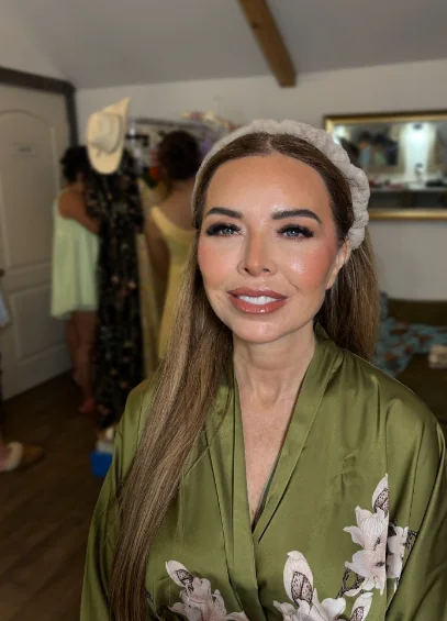 Bridesmaid in an olive satin robe with glowing makeup and a headband